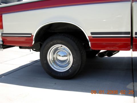 1988 Ford F-150 side view showing rear wheel, chrome hubcap, and dual exhaust pipes