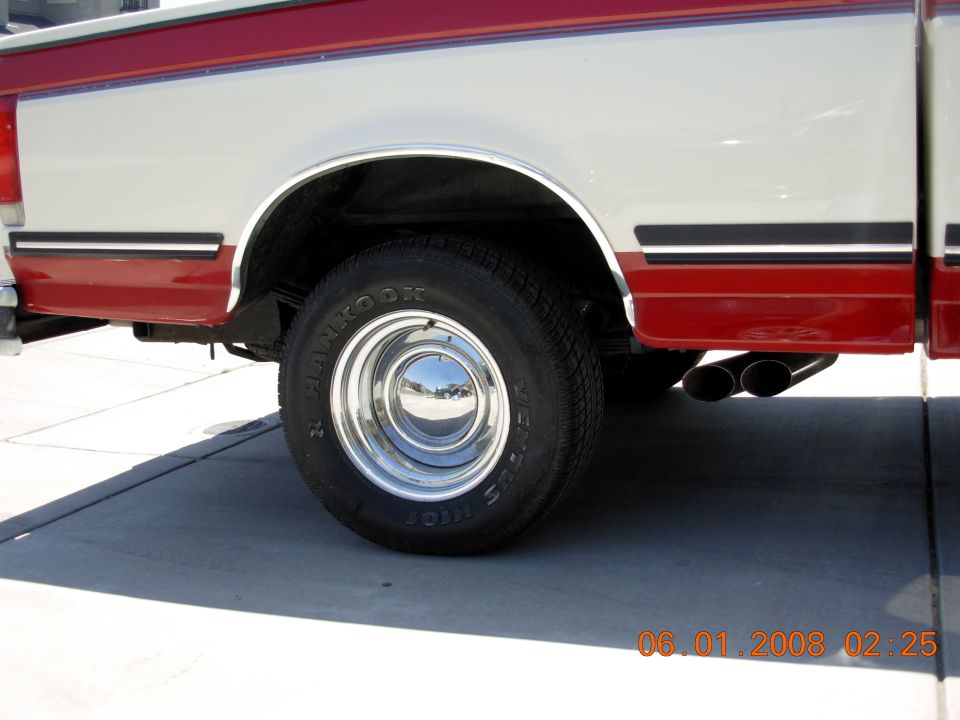 1988 Ford F-150 side view showing rear wheel, chrome hubcap, and dual exhaust pipes