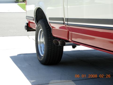 Rear wheel and dual exhaust pipes on a white and red 1988 Ford F-150