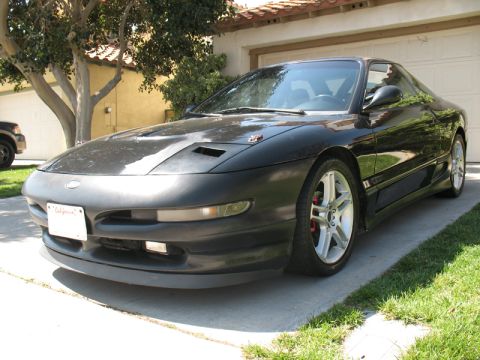 1995 Ford Probe - This black sports coupe is parked in a driveway with a garage in the background.