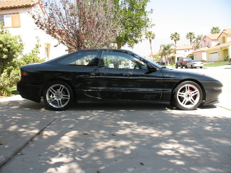 Black Ford Probe GT coupe side view on driveway with five-spoke alloy wheels