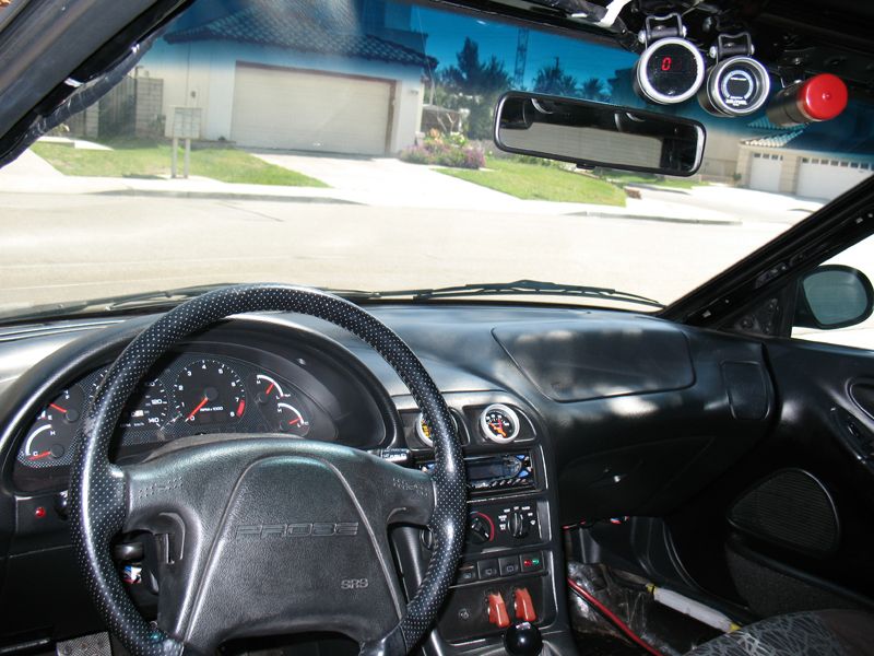 Ford Probe interior with steering wheel, gauges, and aftermarket pods on windshield