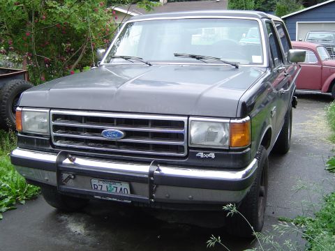 1991 Ford Bronco - A gray 1991 Ford Bronco is parked in a driveway with a red car in the background.