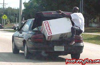 2000 Mercury Grand Marquis - A man loads a large Compaq computer box into the trunk of a black 2000 Mercury Grand Marquis.