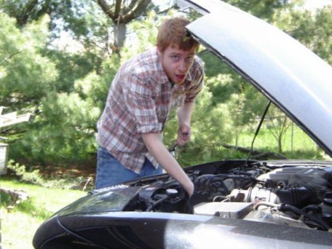 2002 Nissan SE-R - A person is seen working on the engine of a car with the hood open.