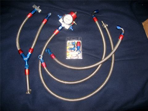 1993 Ford Probe - Fuel pressure regulator kit with braided lines and fittings laid out on a dark surface.