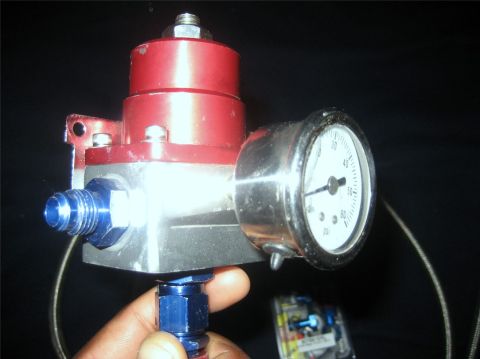 1993 Ford Probe - A close-up view of a fuel pressure regulator and its attached gauge, with a hand holding the part.
