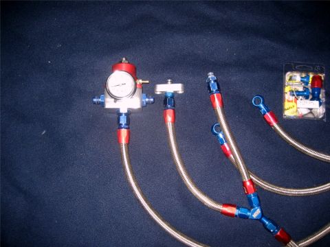 1993 Ford Probe - A fuel pressure regulator kit with braided lines and a gauge is laid out on a dark surface.