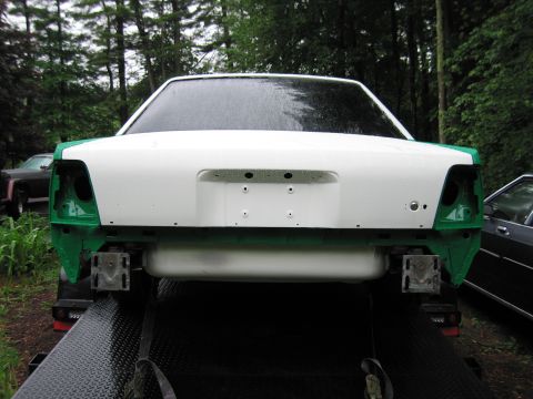 1991 Ford LTD Crown Victoria - A white and green car body is seen from the rear, mounted on a trailer, with its bumper and taillights removed.