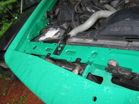 1991 Ford LTD Crown Victoria - Engine bay of a green vehicle, showing the battery, hoses, and a Ford logo on a component.