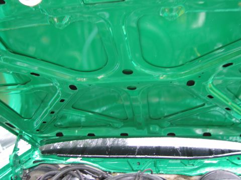1991 Ford LTD Crown Victoria - The underside of a green car hood is shown, revealing structural supports and mounting points.