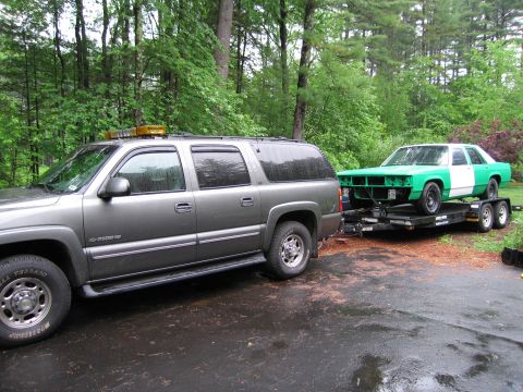 1991 Ford LTD Crown Victoria - A green and white sedan, likely a Ford Crown Victoria, is transported on a trailer towed by a gray Chevrolet Suburban.