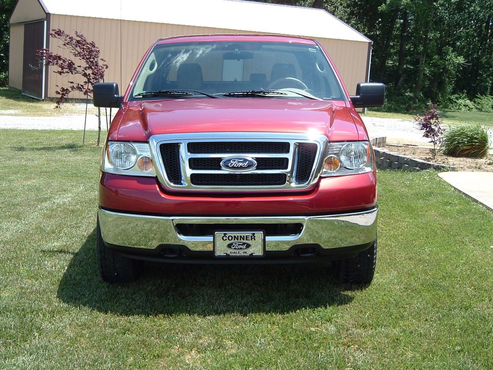 Red Ford F-150 pickup head-on with chrome grille and Conner Ford dealer plate
