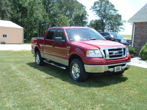 2008 Ford F-150 - Red Ford F-150 pickup truck parked on a lawn, with a second truck visible in the background.