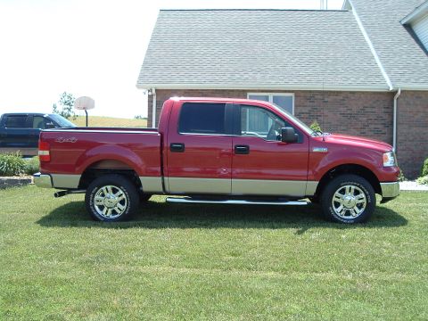 2008 Ford F-150 - A red pickup truck with a tan lower body is parked on a lawn next to a brick house. A second truck is in the background.