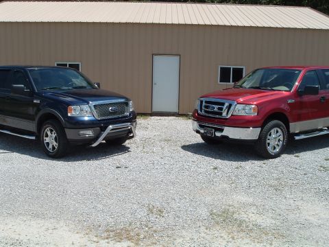2008 Ford F-150 - Two Ford F-150 trucks are parked in front of a tan building with a gravel lot.