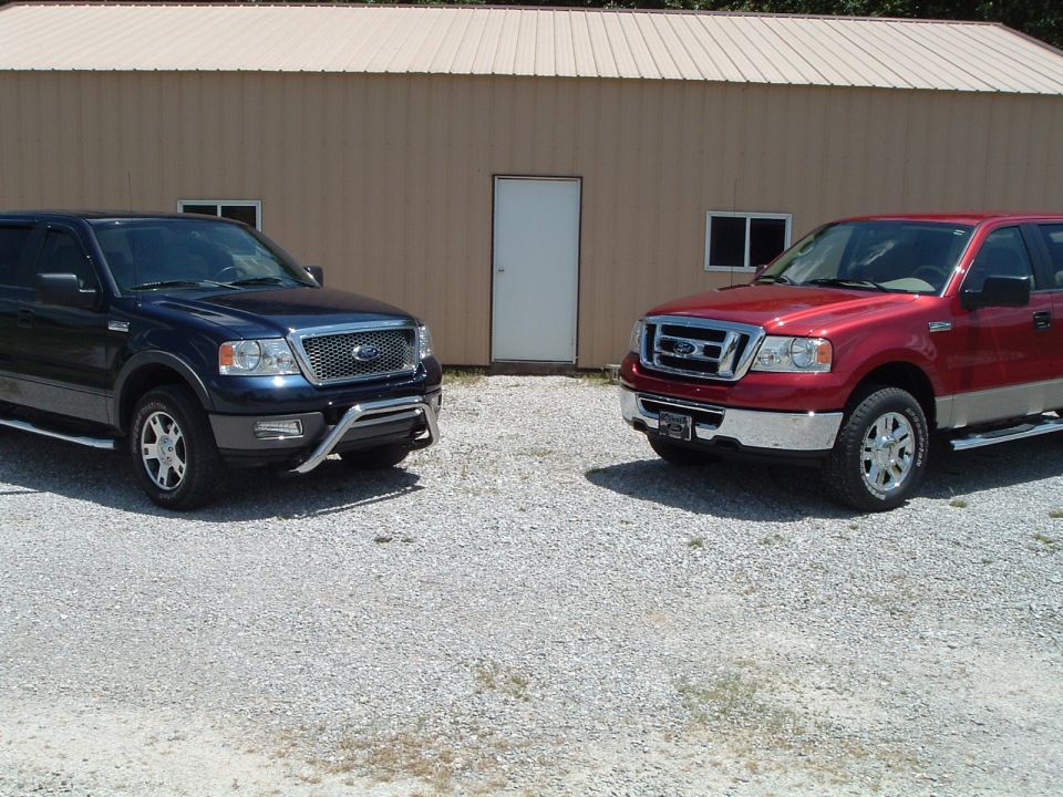 Two Ford F-150 trucks, one blue and one red, parked outside