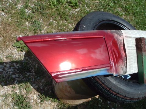1999 Mercury Grand Marquis - A red car door panel is being worked on, with newspaper used as masking tape.