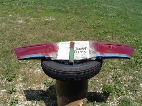 1999 Mercury Grand Marquis - Car fender undergoing paint preparation, supported by a spare tire outdoors.