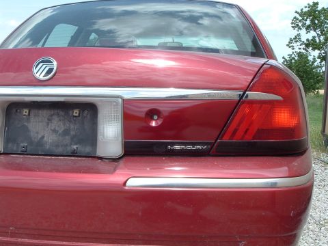 1999 Mercury Grand Marquis - Rear view of a red Mercury Grand Marquis with visible taillights and chrome accents.