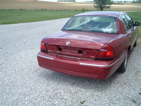 1999 Mercury Grand Marquis - This red sedan, likely a 1998 model, is missing its rear bumper and license plate lights.