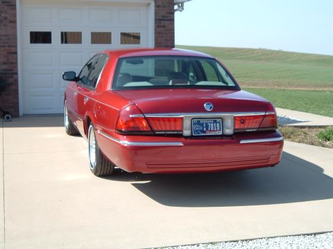 1999 Mercury Grand Marquis - Rear view of a red 1999 Mercury Grand Marquis sedan parked on a concrete driveway.