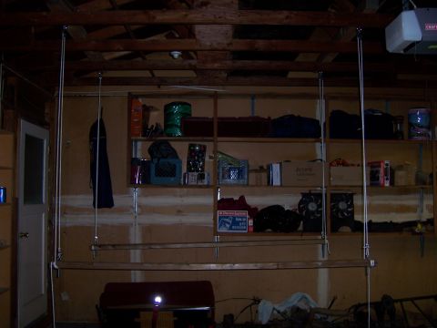 1991 Ford Bronco - A cluttered garage scene with shelves stocked with supplies and a wooden plank hanging from the ceiling.