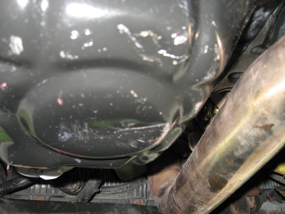 Underside of a vehicle showing an oil pan and exhaust pipe.