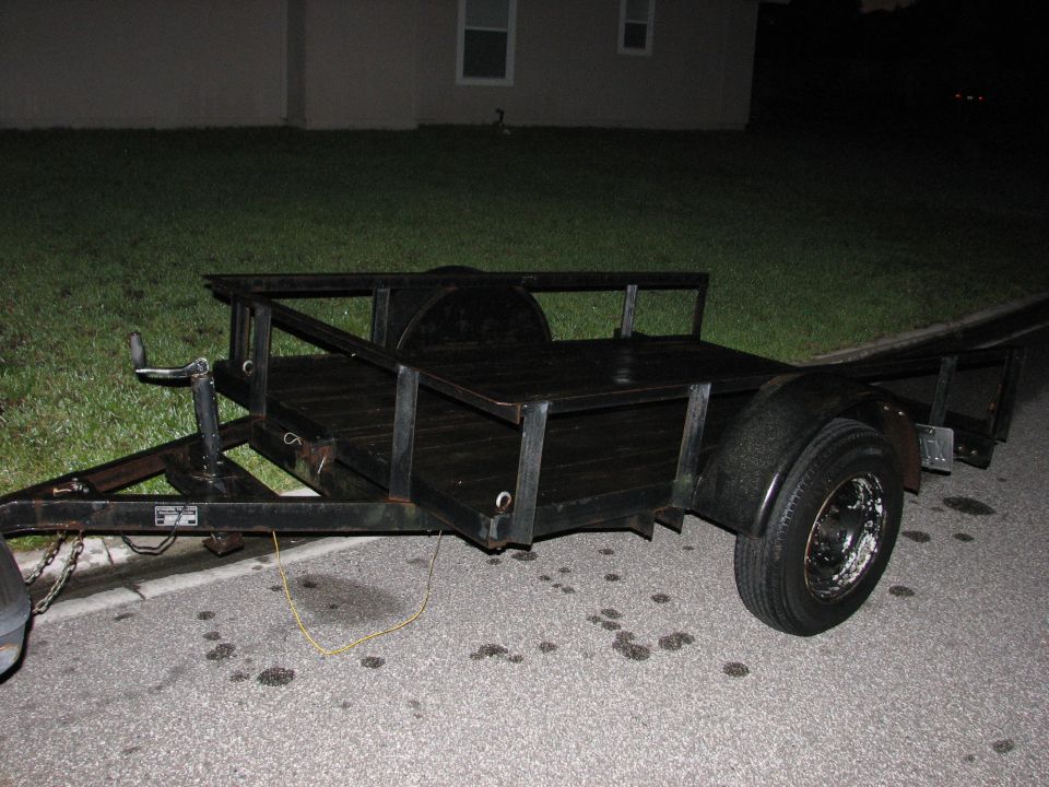 Black utility trailer with wooden deck and single axle.