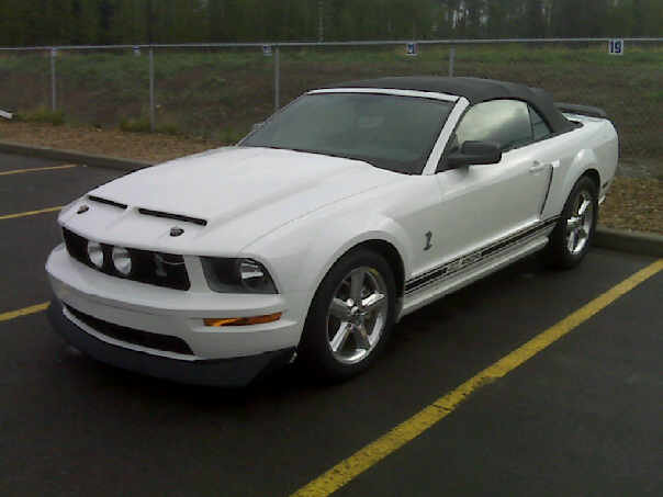 White Ford Mustang convertible with black top parked in a lot