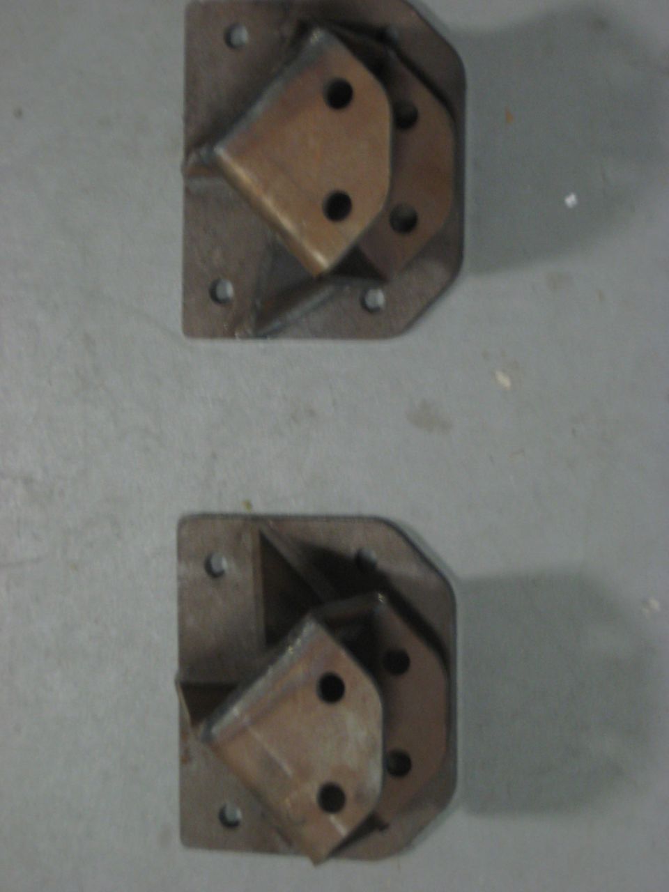 Two metal brackets on a gray concrete floor