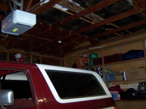 1991 Ford Bronco - A red and white 1991 Ford Bronco is parked inside a garage, with shelves and a garage door opener visible.