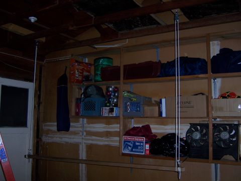 1991 Ford Bronco - A cluttered garage interior features shelves filled with various storage items, including bins, boxes, and fans.