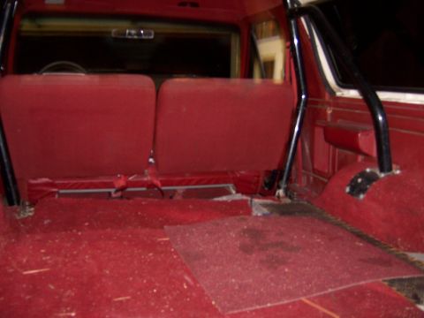 1991 Ford Bronco - The interior of a vehicle shows red seats and carpeting, with a roll bar visible.
