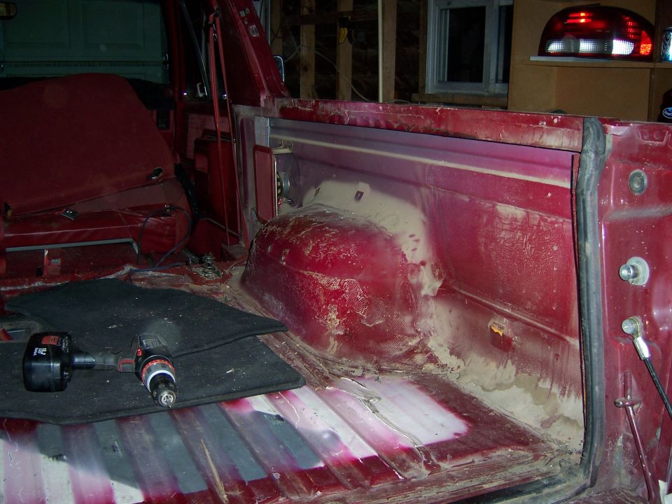 Interior of red vehicle with seats removed, showing floor and wheel well