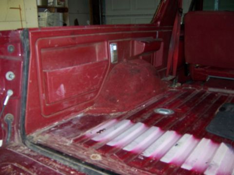 1991 Ford Bronco - The interior of a red SUV shows the cargo area with red side paneling and a ribbed floor.