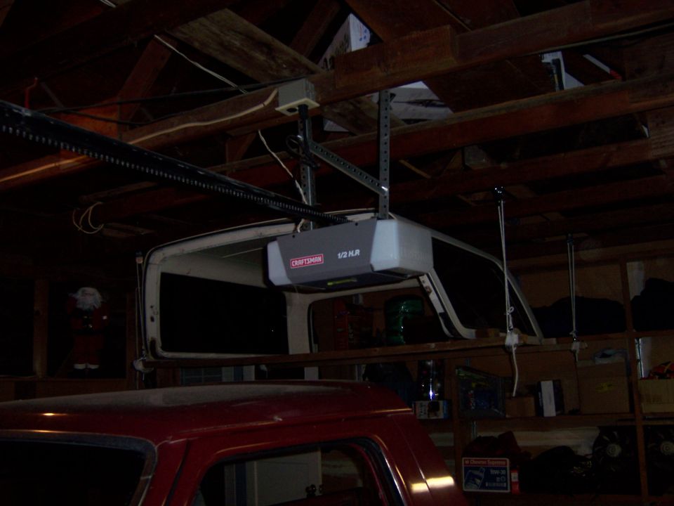 red car roof below a white vehicle top and a garage door opener