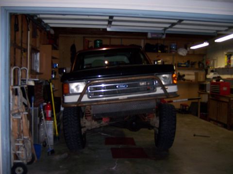 1991 Ford Bronco - A lifted Ford Bronco sits in a garage, equipped with a heavy-duty custom front bumper.