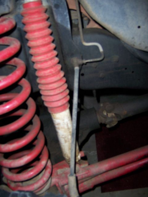 1991 Ford Bronco - Close-up view of red coil springs and a red-booted shock absorber, indicative of a high-lift suspension modification.