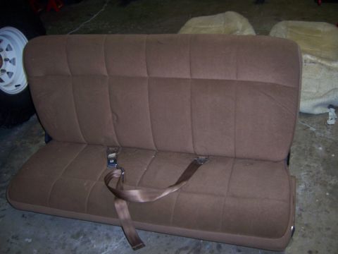 1991 Ford Bronco - A brown bench seat with seatbelts is shown, with other car parts in the background.