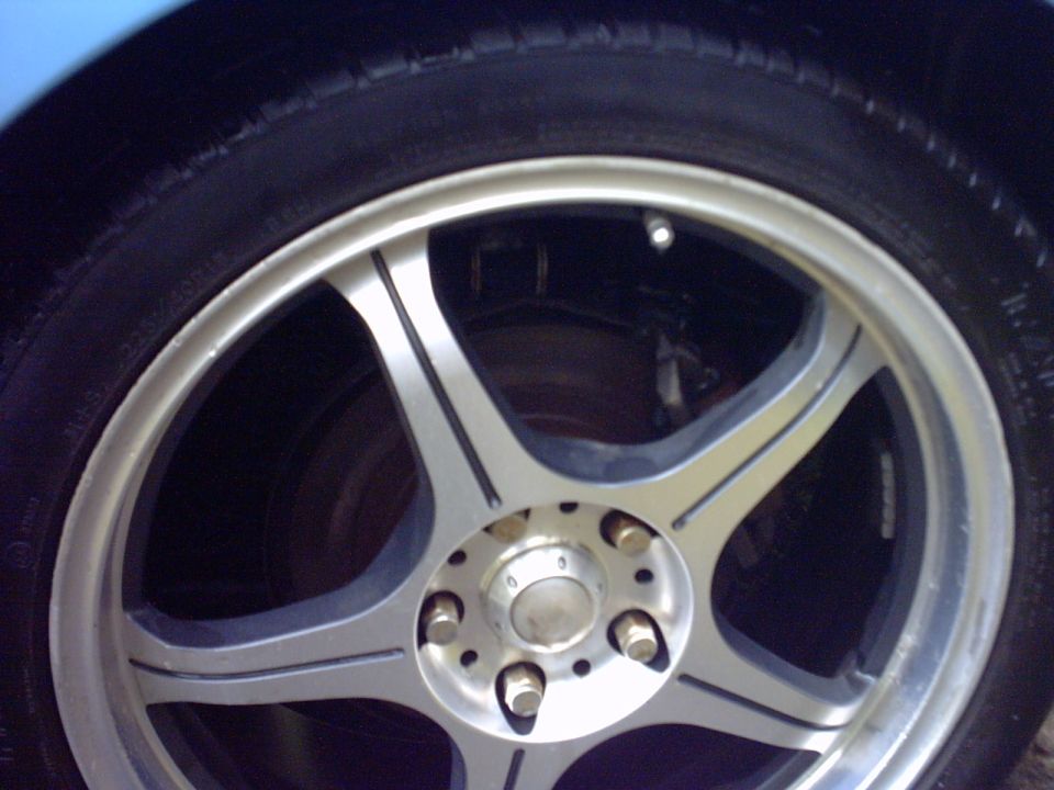 Close-up of a five-spoke silver alloy wheel with low-profile tire and visible lug nuts