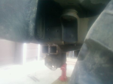 1988 Ford Bronco - Undercarriage view of a vehicle's frame and suspension, with a jack providing support.