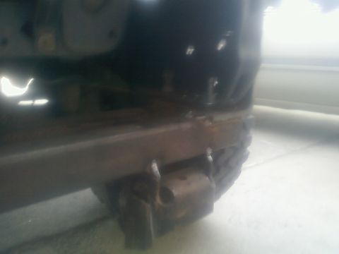 1988 Ford Bronco - Close-up of a rusted metal frame section, showing tire tread in the background.