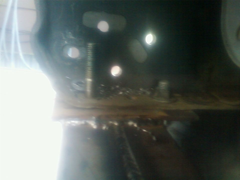 Close-up of a vehicle's frame with drilled holes and bolts, possibly modified