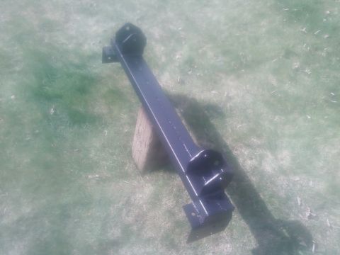 1988 Ford Bronco - A black metal frame part, possibly a bumper or chassis component, is shown outdoors on a grassy area.