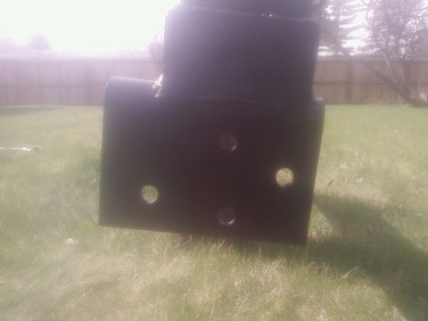 1988 Ford Bronco - A close-up view of a black metal bracket with circular holes, placed outdoors on a grassy area.