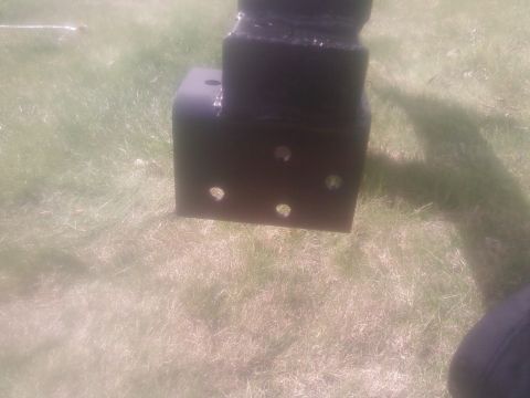 1988 Ford Bronco - A close-up view of a black metal bracket with multiple holes, resting on grass.