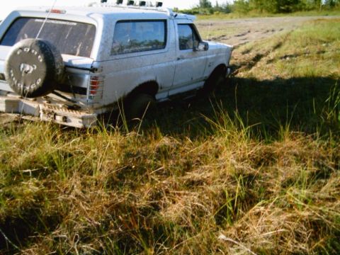 1995 Ford Bronco - This 1995 Ford Bronco is stuck in the mud, with its rear end partially submerged in the wet terrain.