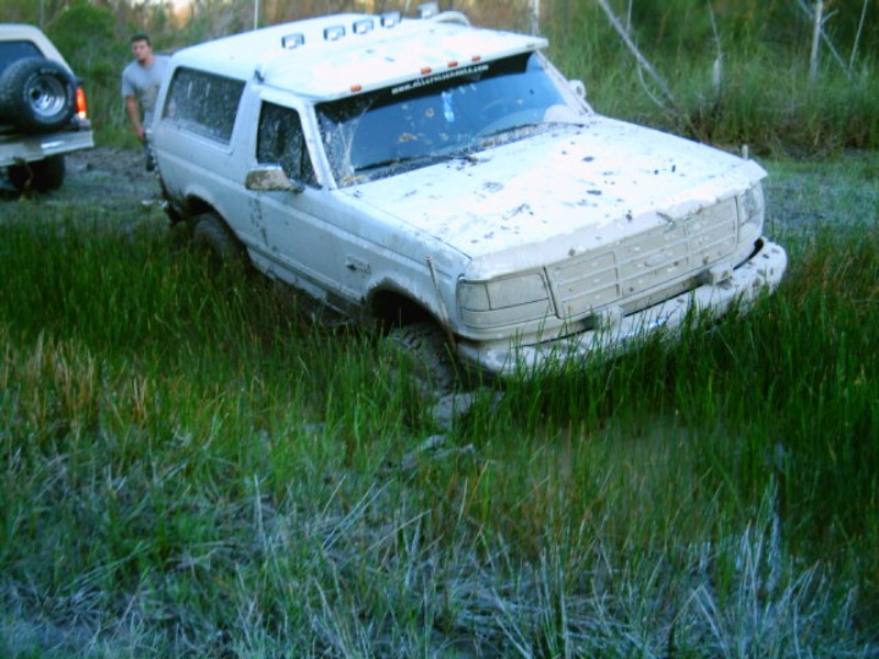 White 1995 Ford Bronco stuck in mud, 3q-front view