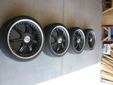 1996 Ford Probe - Four aftermarket alloy wheels and tires are lined up on a concrete surface, possibly in a garage.